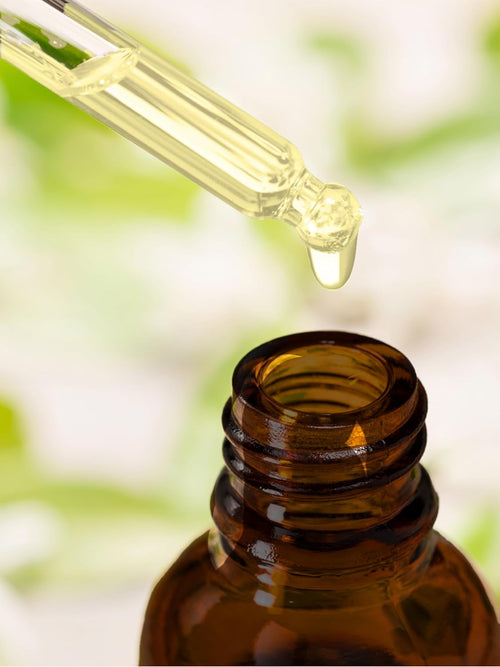 Brown glass bottle with dropper against a blurred green background