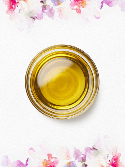 Glass bowl of yellow liquid on a white background with floral accents