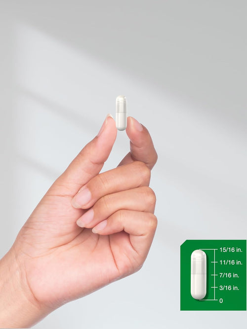 Hand holding a white capsule with a measurement chart on a gray background